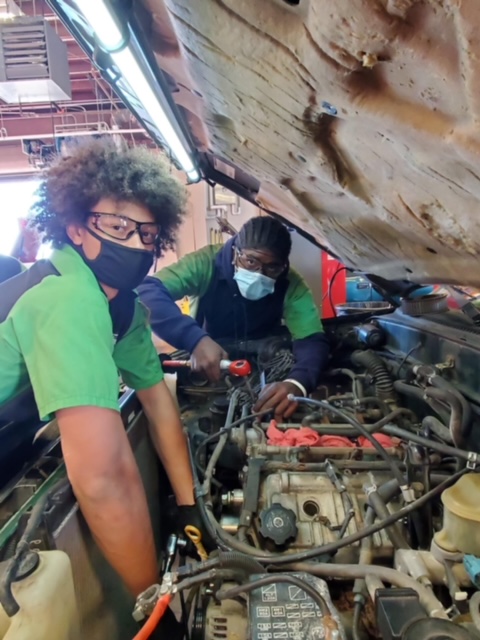 KISD Career Center students working inside of a car, under the hood